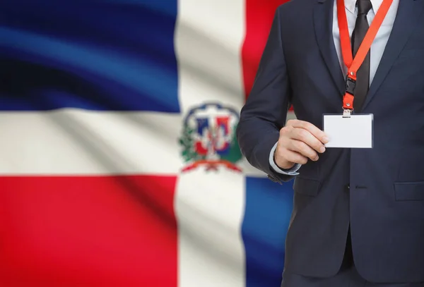 Biznesmen gospodarstwa karta identyfikator na smyczy z flagi narodowej na tle - Dominikana — Zdjęcie stockowe