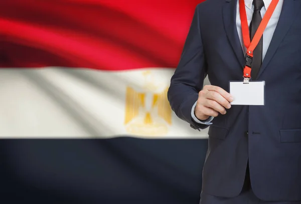 Uomo d'affari holding badge in carta su un cordino con una bandiera nazionale su priorità bassa - Egitto — Foto Stock