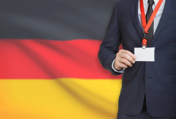 Uomo d'affari holding badge in carta su un cordino con una bandiera nazionale su priorità bassa - Germania — Foto Stock