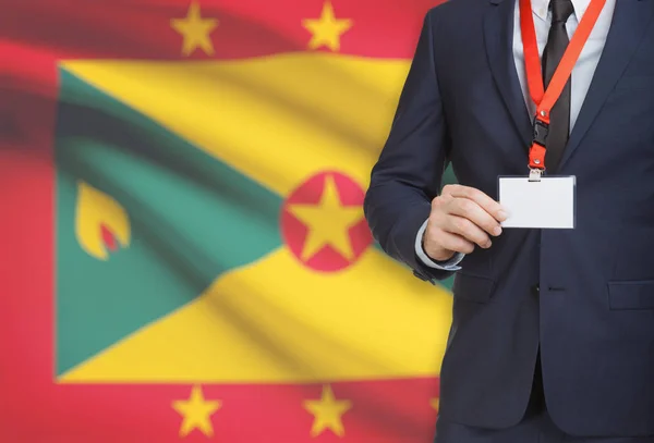 Biznesmen gospodarstwa karta identyfikator na smyczy z flagi narodowej na tle - Grenada — Zdjęcie stockowe