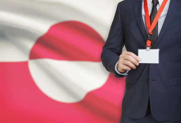 Empresário, segurando o distintivo de cartão nome em uma corda com uma bandeira nacional no plano de fundo - Gronelândia — Fotografia de Stock
