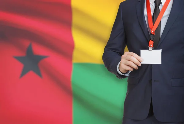 Businessman holding name card badge on a lanyard with a national flag on background - Guinea-Bissau — Stock Photo, Image