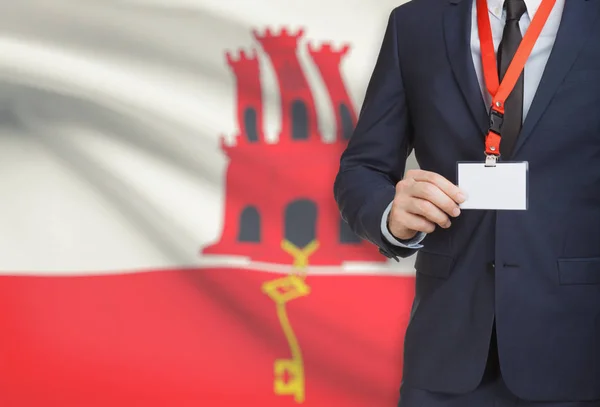 Empresário, segurando o distintivo de cartão nome em uma corda com uma bandeira nacional no plano de fundo - Gibraltar — Fotografia de Stock