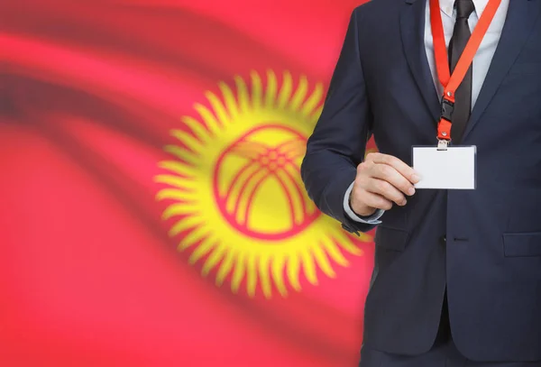 Businessman holding name card badge on a lanyard with a national flag on background - Kyrgyzstan — Stock Photo, Image