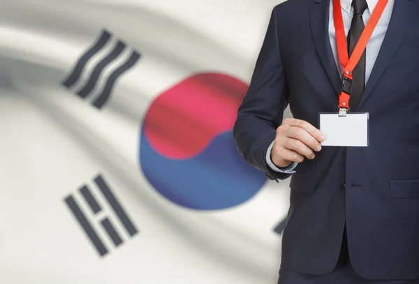 Επιχειρηματίας που κατέχουν κάρτα διακριτικό όνομα σε ένα κορδόνι με μια εθνική σημαία σε φόντο - Νότια Κορέα — Φωτογραφία Αρχείου