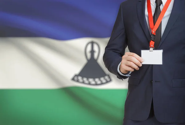Geschäftsmann hält Namensschild Karte auf ein Schlüsselband mit einer Nationalflagge auf Hintergrund - Lesotho — Stockfoto