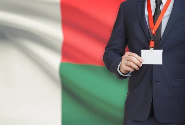 Geschäftsmann hält Namensschild Karte auf ein Schlüsselband mit einer Nationalflagge auf Hintergrund - Madagaskar — Stockfoto