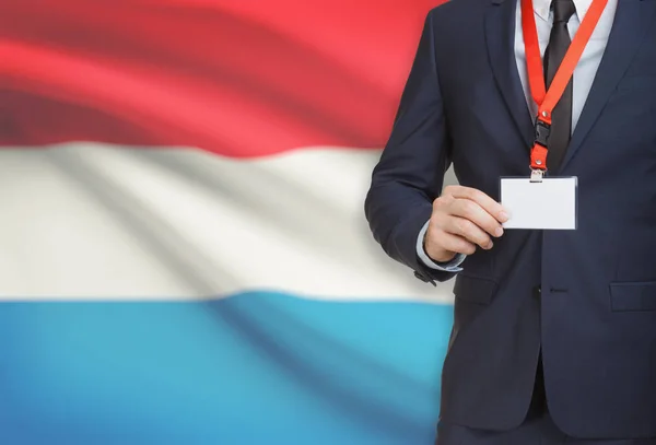 Empresário, segurando o distintivo de cartão nome em uma corda com uma bandeira nacional no plano de fundo - Luxemburgo — Fotografia de Stock