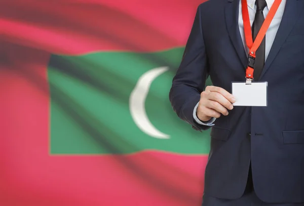 Podnikatel, drží karty jmenovku na krk s národní vlajkou na pozadí - Maledivy — Stock fotografie