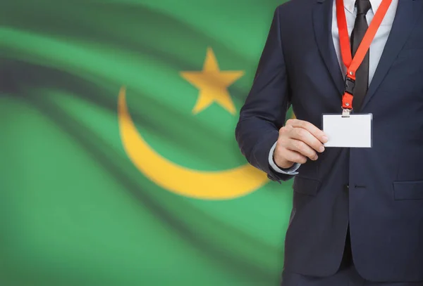 Empresario con credencial de la tarjeta en una cuerda con una bandera nacional de fondo - Mauritania — Foto de Stock