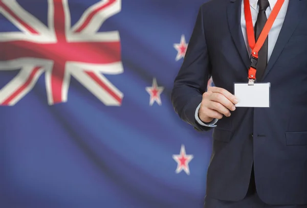 Empresário, segurando o distintivo de cartão nome em uma corda com uma bandeira nacional no plano de fundo - Nova Zelândia — Fotografia de Stock