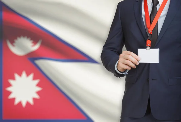 Empresário, segurando o distintivo de cartão nome em uma corda com uma bandeira nacional no plano de fundo - Nepal — Fotografia de Stock