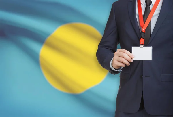Geschäftsmann, ein Schlüsselband mit einer Nationalflagge auf Hintergrund - Palau Karte Namensschild festhalten — Stockfoto