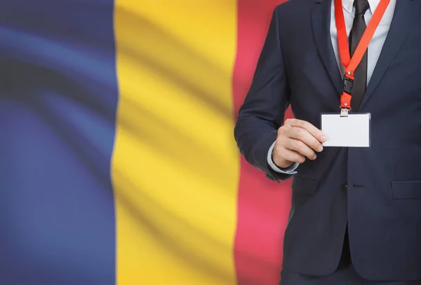 Empresario sosteniendo credencial tarjeta en una cuerda con una bandera nacional de fondo - Rumania —  Fotos de Stock