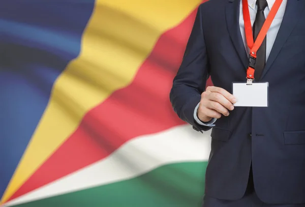 Geschäftsmann, ein Schlüsselband mit einer Nationalflagge auf Hintergrund - Seychellen Karte Namensschild festhalten — Stockfoto