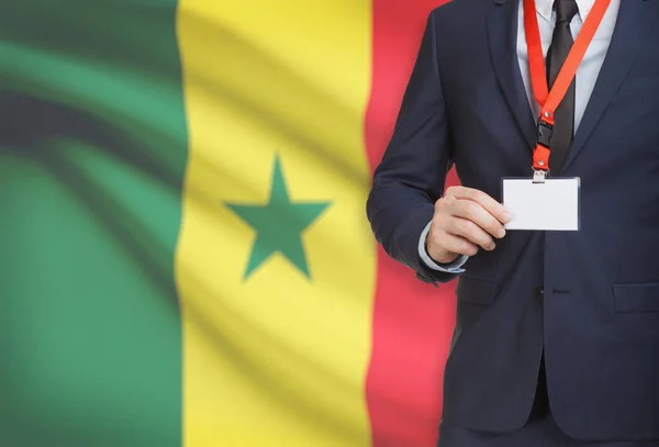 Biznesmen gospodarstwa karta identyfikator na smyczy z flagi narodowej na tle - Senegal — Zdjęcie stockowe