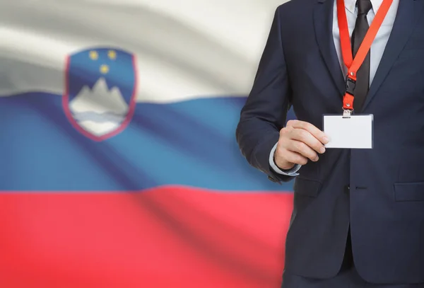 Zakenman kaart naambadge te houden op een lanyard met een nationale vlag op de achtergrond - Slovenië — Stockfoto