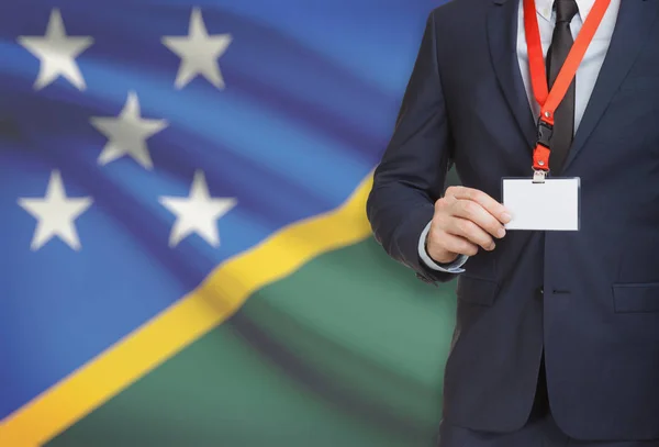 Affärsman som innehar kortet namnskylt på en snodd med en flagga på bakgrunden - Salomonöarna — Stockfoto