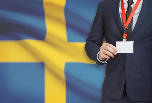 Empresario con credencial de la tarjeta en una cuerda con una bandera nacional de fondo - Suecia —  Fotos de Stock