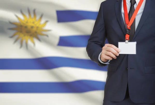 Homme d’affaires détenant des porte-nom carte sur une longe munie d’un drapeau national sur fond - Uruguay — Photo