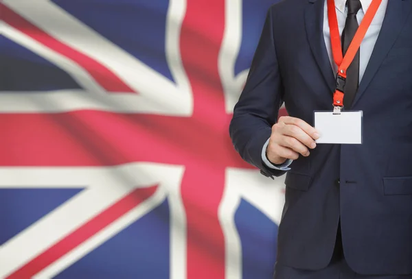 Businessman holding name card badge on a lanyard with a national flag on background - United Kingdom — Stock Photo, Image