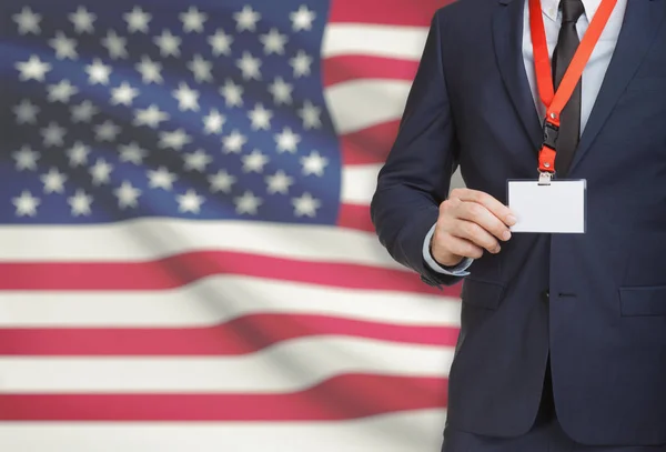 Businessman holding name card badge on a lanyard with a national flag on background - United States — Stock Photo, Image