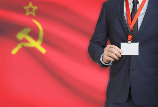 Empresario sosteniendo credencial tarjeta en una cuerda con una bandera nacional de fondo - Unión Soviética - URSS — Foto de Stock