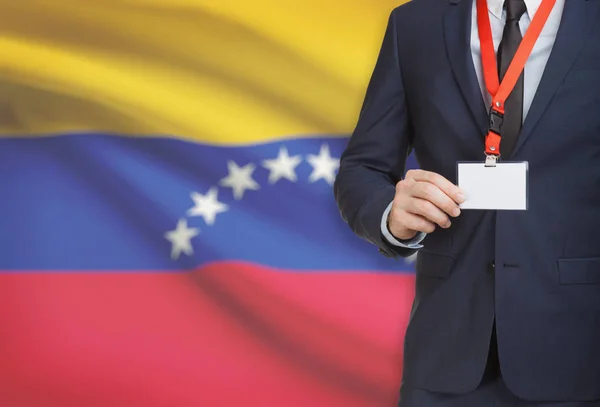 Businessman holding name card badge on a lanyard with a national flag on background - Venezuela — Stock Photo, Image