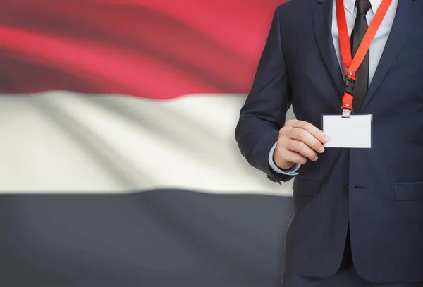 Businessman holding name card badge on a lanyard with a national flag on background - Yemen