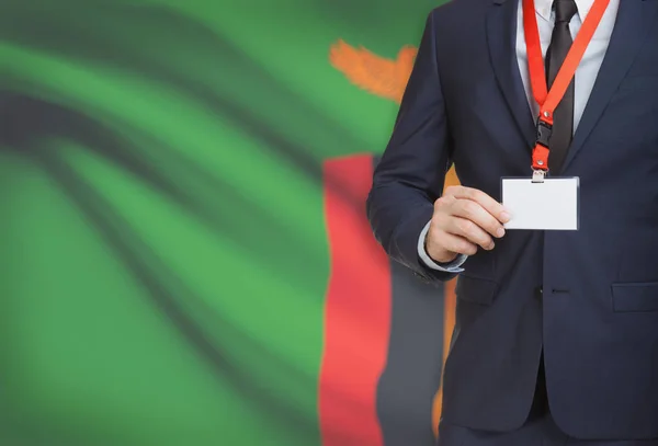 Бізнесмен, проведення карти бедж на ремінь з національного прапора на фоні - Замбія — стокове фото