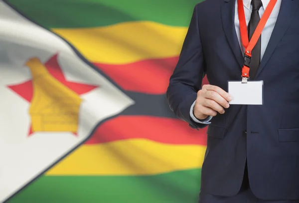 Businessman holding name card badge on a lanyard with a national flag on background - Zimbabwe — Stock Photo, Image