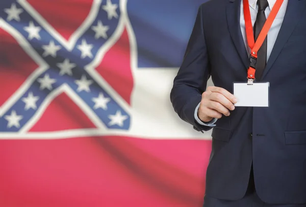 Empresario celebración tarjeta de identificación en un elemento de amarre con bandera de estado de Estados Unidos en el fondo - Mississippi —  Fotos de Stock