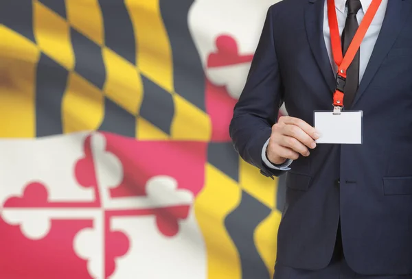 Affärsman innehav märke på en snodd med Usa statsflagga på bakgrunden - Maryland — Stockfoto