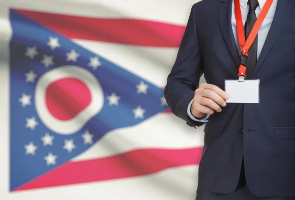 Affärsman innehav märke på en snodd med Usa statsflagga på bakgrunden - Ohio — Stockfoto