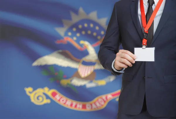 Empresario celebración tarjeta de identificación en un elemento de amarre con bandera de estado de Estados Unidos en el fondo - Dakota del norte —  Fotos de Stock