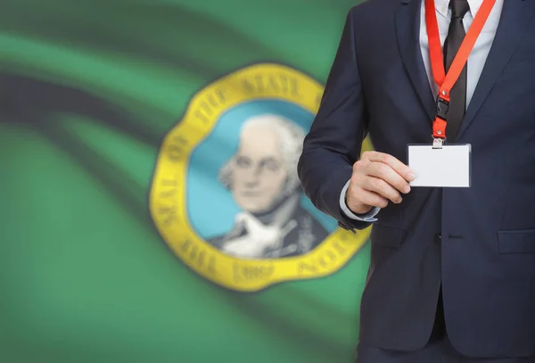 Empresario celebración tarjeta de identificación en un elemento de amarre con bandera de estado de Estados Unidos en el fondo - Washington — Foto de Stock