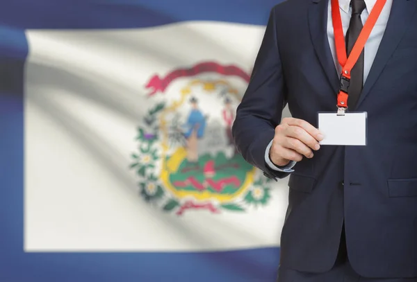 Empresario celebración tarjeta de identificación en un elemento de amarre con bandera de estado de Estados Unidos en el fondo - Virginia Occidental — Foto de Stock