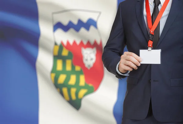 Badge de holding homme d’affaires sur une longe avec le drapeau de la province canadienne sur fond - Territoires du Nord-Ouest — Photo