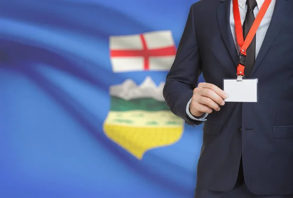 Distintivo de exploração do empresário em uma corda com a bandeira da província canadense em fundo - Alberta — Fotografia de Stock