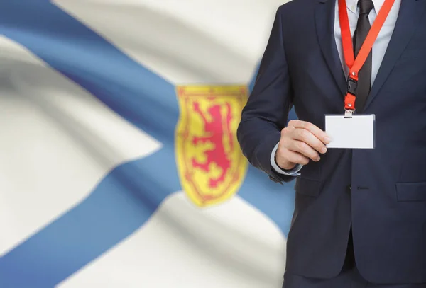 Geschäftsmann Holding Abzeichen auf ein Schlüsselband mit kanadischen Provinz Flagge auf Hintergrund - Nova Scotia — Stockfoto