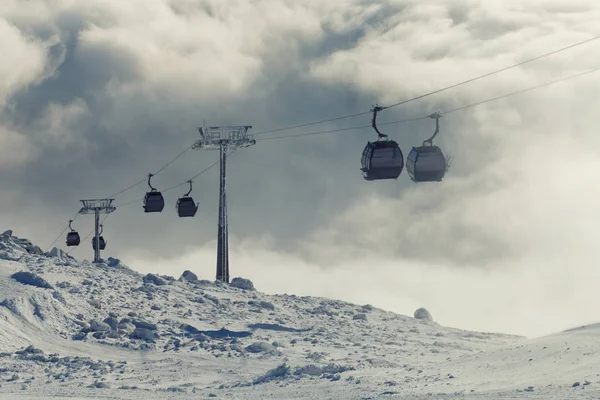 Kabelbaan hutten gaan op en neer hoog in de bergen op een wintersportgebied resort op een bewolkte dag — Stockfoto