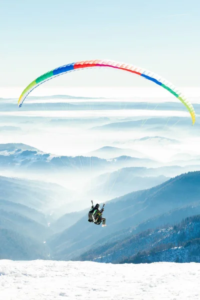 Parapentes lanzaron al aire desde la ladera Nevada de una montaña —  Fotos de Stock