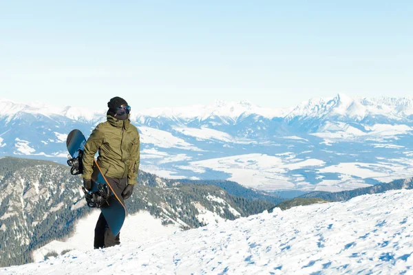 男性的滑雪板，握着他的董事会在手，爬到山顶 — 图库照片