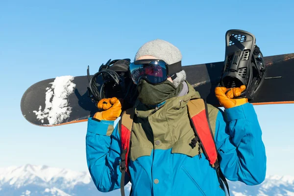 Αρσενικό snowboarder κρατώντας Διοικητικό Συμβούλιο πίσω από τον sholders στην κορυφή του βουνού — Φωτογραφία Αρχείου