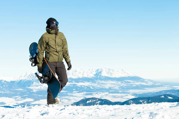 Hombre snowboarder sostienen su tarjeta en la mano y dar un paseo a la cima de una montaña —  Fotos de Stock