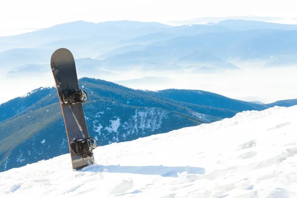 Snowboard thrusted in snö på toppen av ett berg — Stockfoto