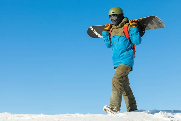 Snowboarder joven dando un paseo en lo alto de una montaña con el hermoso cielo de fondo —  Fotos de Stock