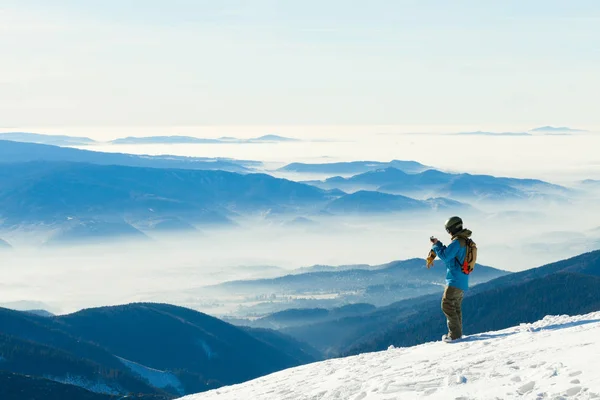 Mannelijke snowboarder nemen foto van het prachtige landschap van de top van een berg — Stockfoto