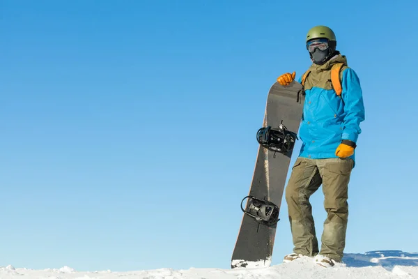 Junge Snowboarder im Helm an der Spitze eines Berges mit schönen Himmel Hintergrund — Stockfoto