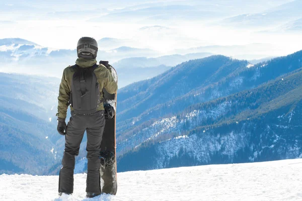 Jonge snowboarder permanent naast snowboard stuwkracht in sneeuw en kijken naar een mooi berglandschap — Stockfoto